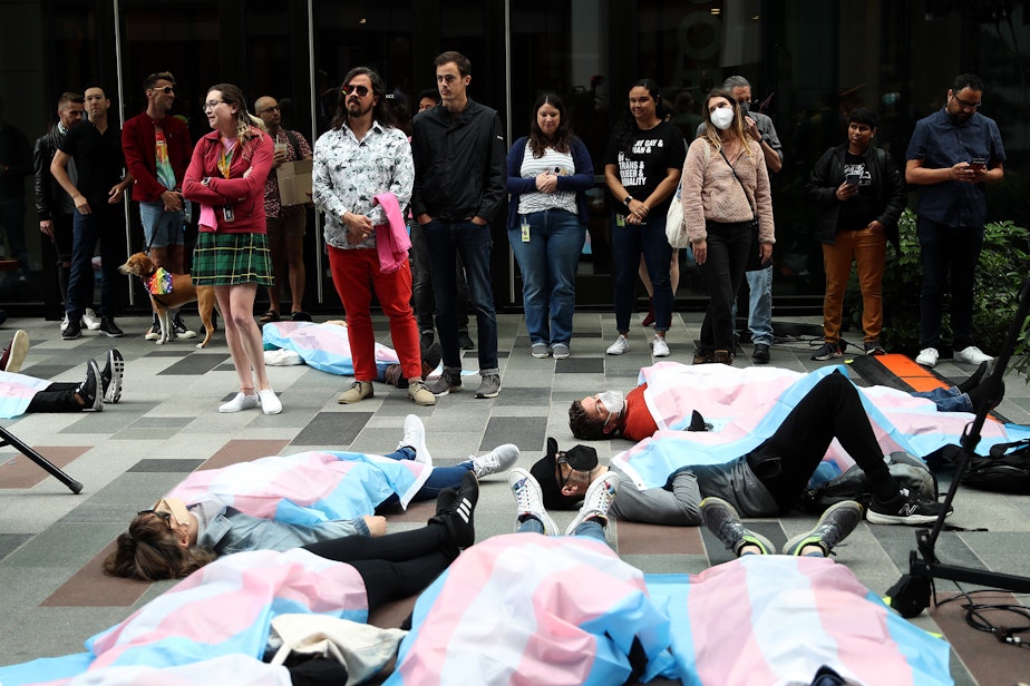 caption: Trans Amazon workers and allies stage a die-in protest as the company began a Pride flag raising ceremony on Wednesday, June 1, 2022, in Seattle. 