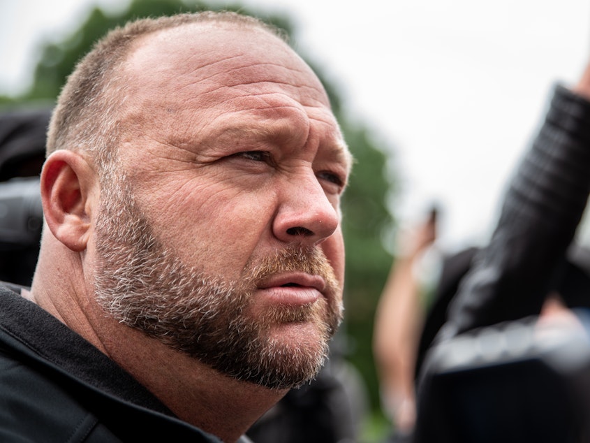 caption: Infowars founder Alex Jones listens to a supporter at the Texas State Capital building on April 18, 2020 in Austin, Texas.