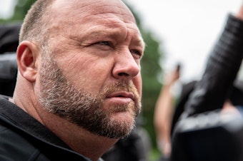 caption: Infowars founder Alex Jones listens to a supporter at the Texas State Capital building on April 18, 2020 in Austin, Texas.