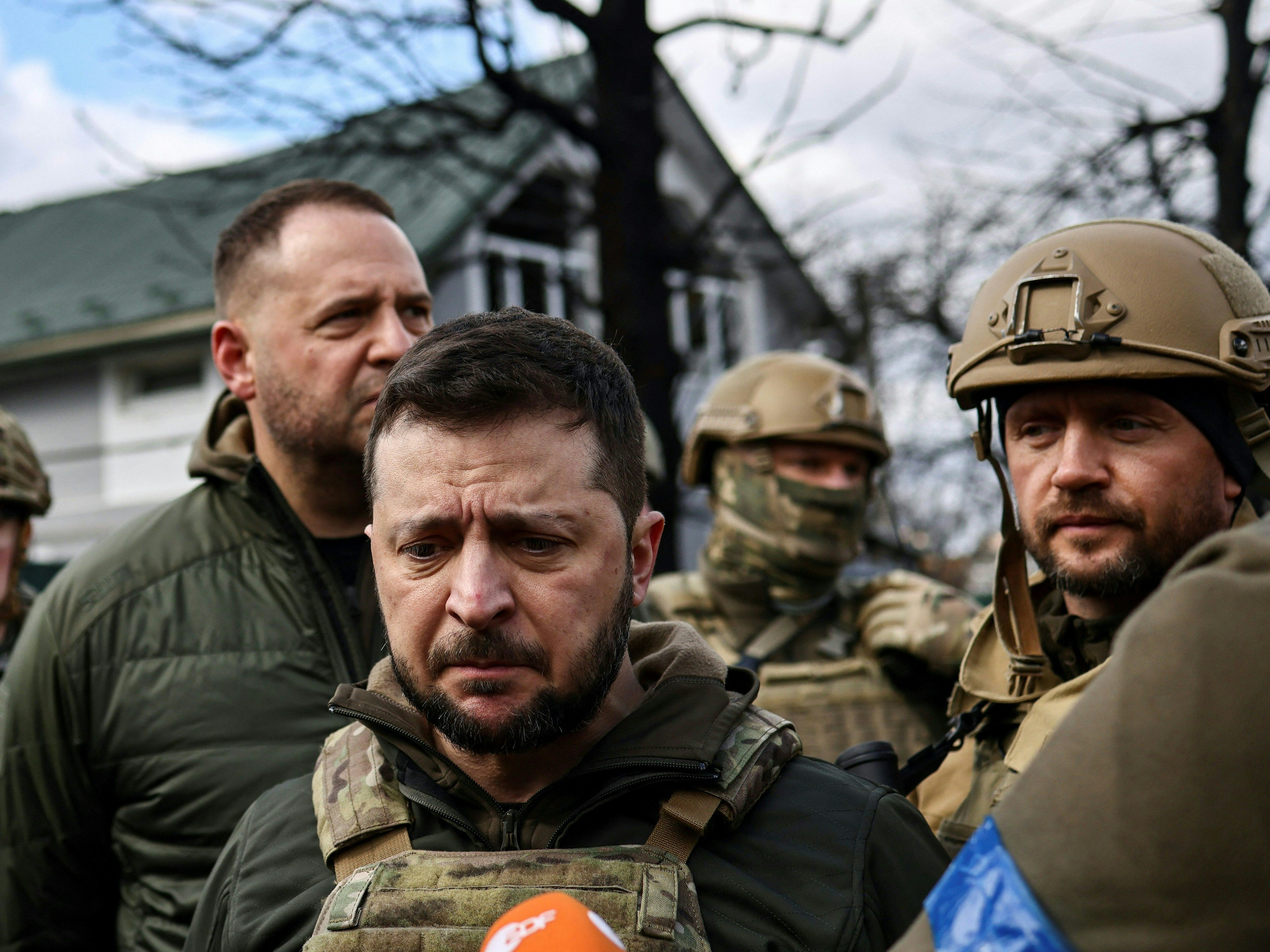 caption: Ukainian President Volodymyr Zelenskyy, center, speaks to the press in the town of Bucha on the northwest edge of the Ukrainian capital Kyiv on Monday.