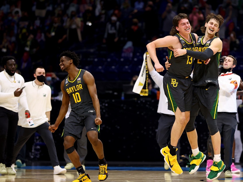 caption: Baylor players Adam Flagler #10, Matthew Mayer #24 and Jackson Moffatt #13 celebrate after defeating the Gonzaga Bulldogs in the National Championship game of the 2021 NCAA Men's Basketball Tournament at Lucas Oil Stadium.
