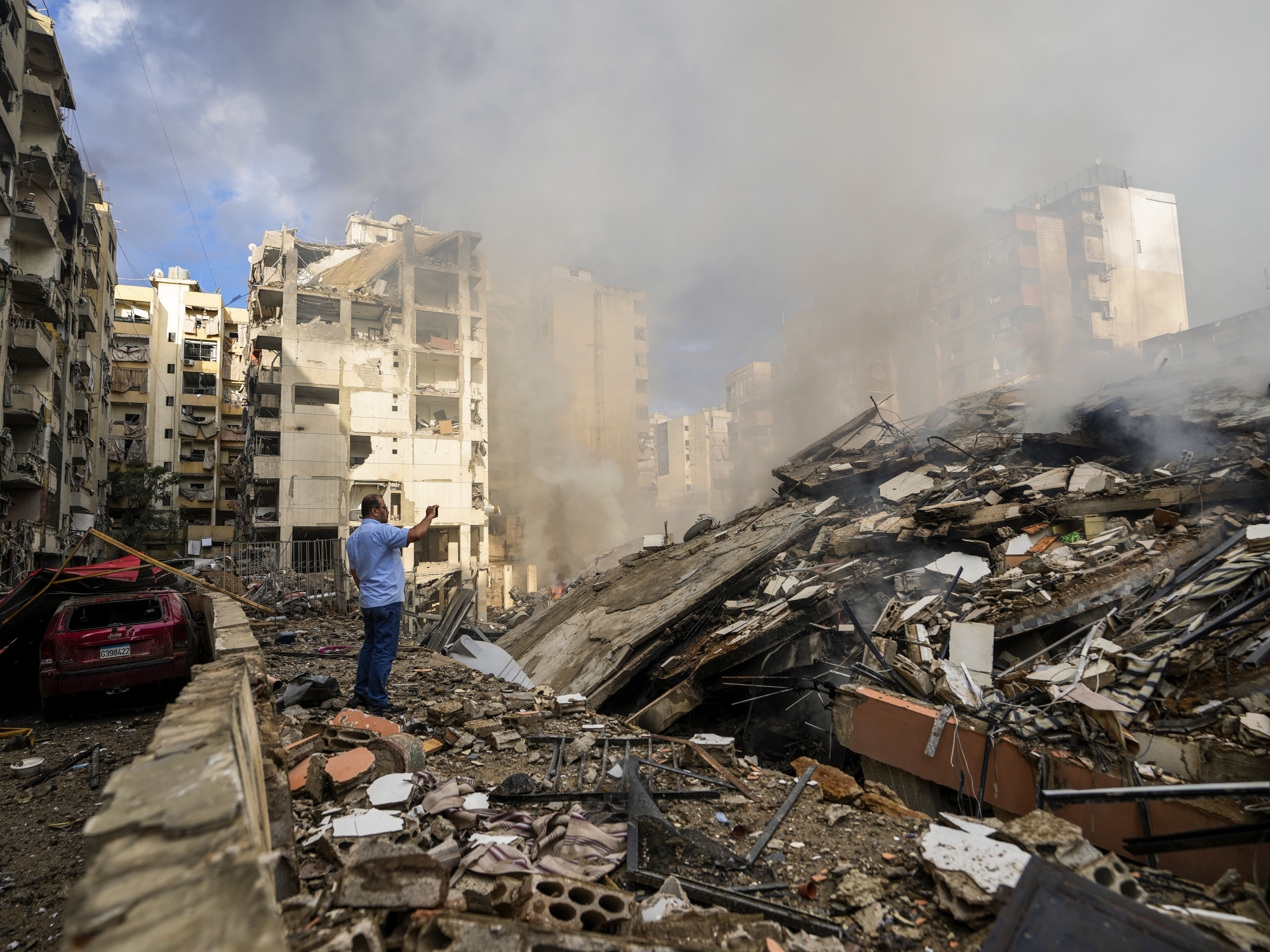 caption: A man documents destroyed buildings at the site of an Israeli airstrike in Beirut's southern suburb, Lebanon, on Tuesday.