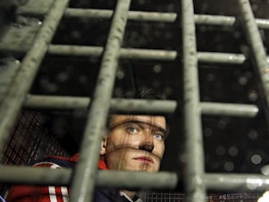 caption: Alexei Navalny is seen in 2012 behind the bars in a police van after he was detained during protests in Moscow a day after Vladimir Putin's inauguration.