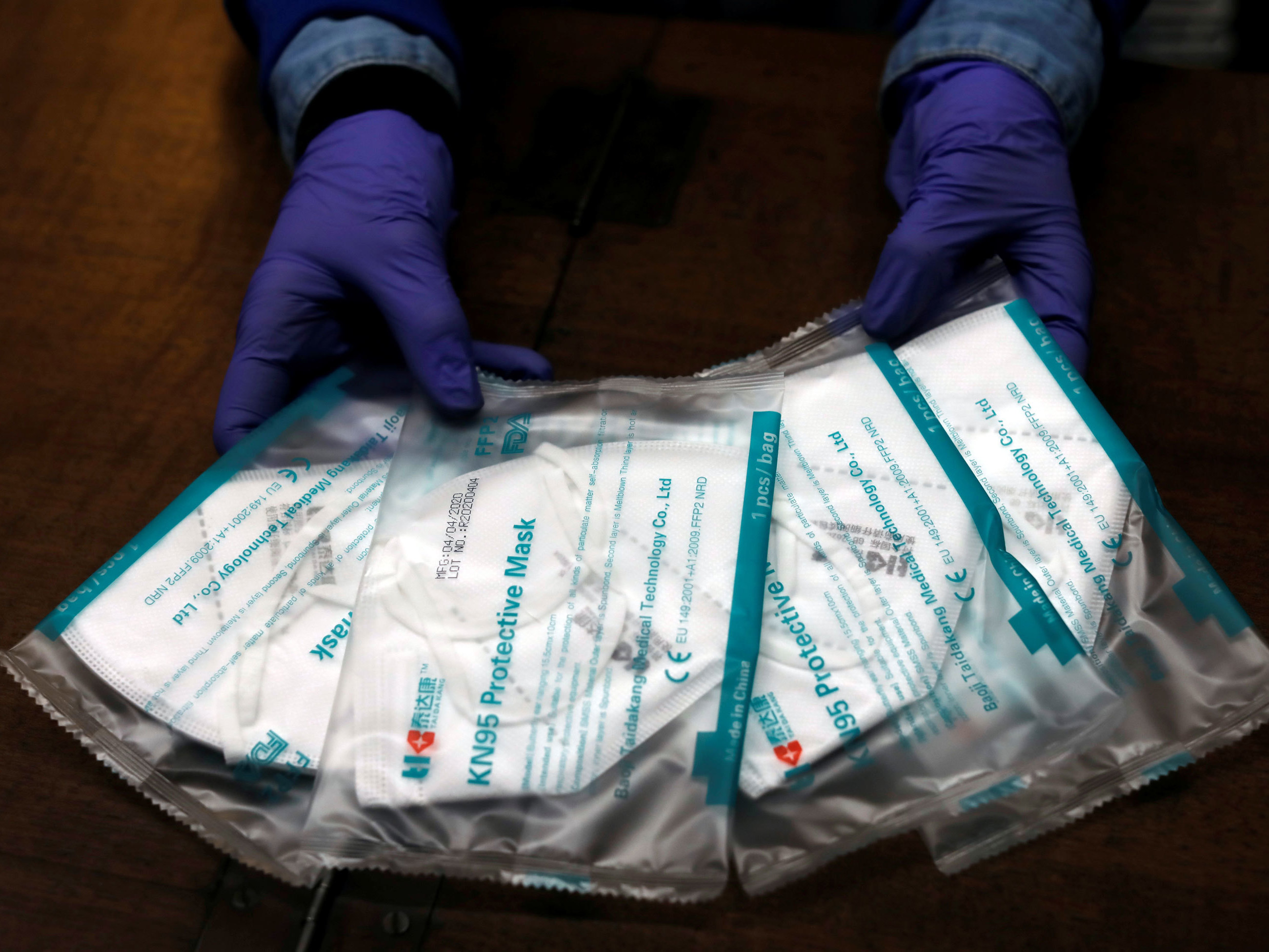 caption: A pharmacy employee shows KN95 protective face masks that were made in China. Companies like Golden Pacific Fashion and Design in Shanghai, which used to sell curtains, have pivoted to making KN95 masks like these.