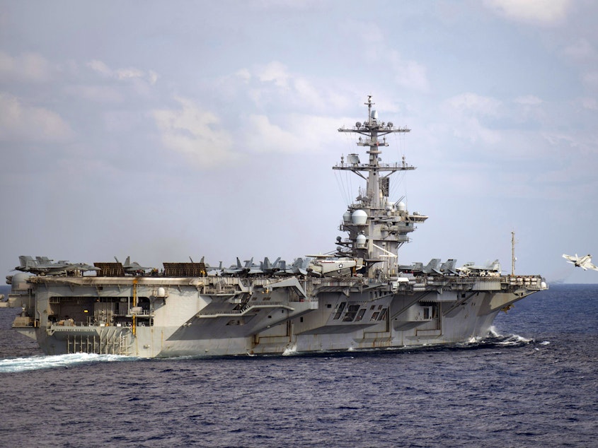 caption: The aircraft carrier USS Theodore Roosevelt is in the western North Pacific Ocean on March 18. The Navy has recommended reinstatement of the ship's captain who was fired after pleading for help with the coronavirus infection onboard.