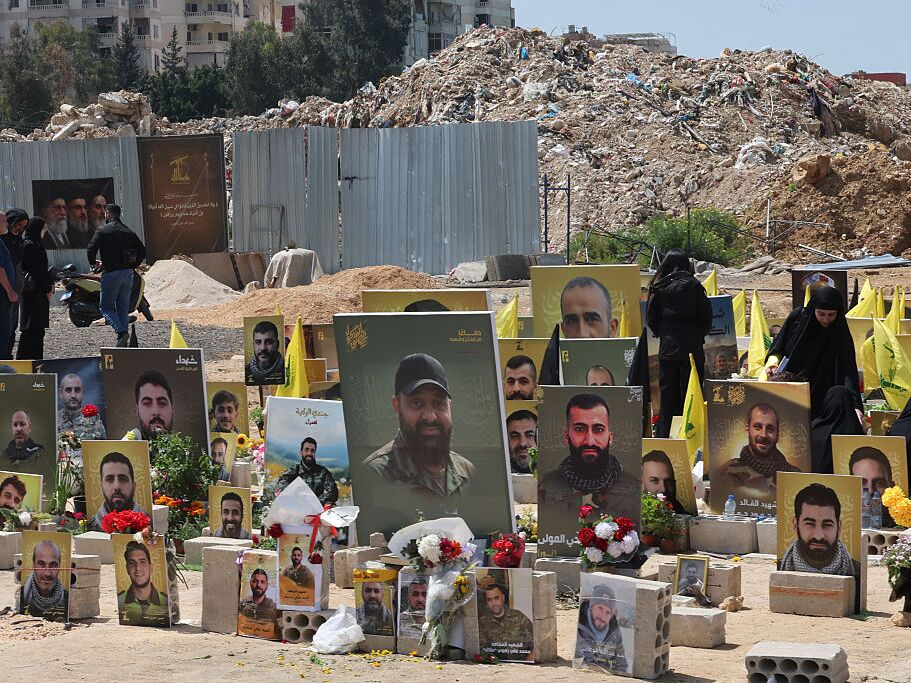 caption: People at a cemetery in Choueifat on Monday stand amid the graves of Hezbollah fighters killed in Israeli strikes.