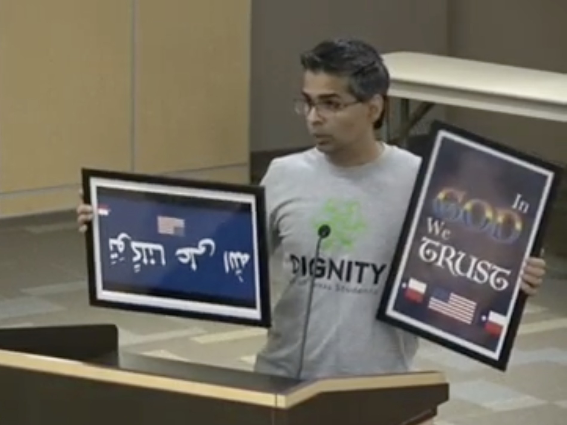 caption: "Why is more God not good?" asked Srivan Krishna, as he sought to donate colorful "In God We Trust" signs at a school board meeting earlier this week.