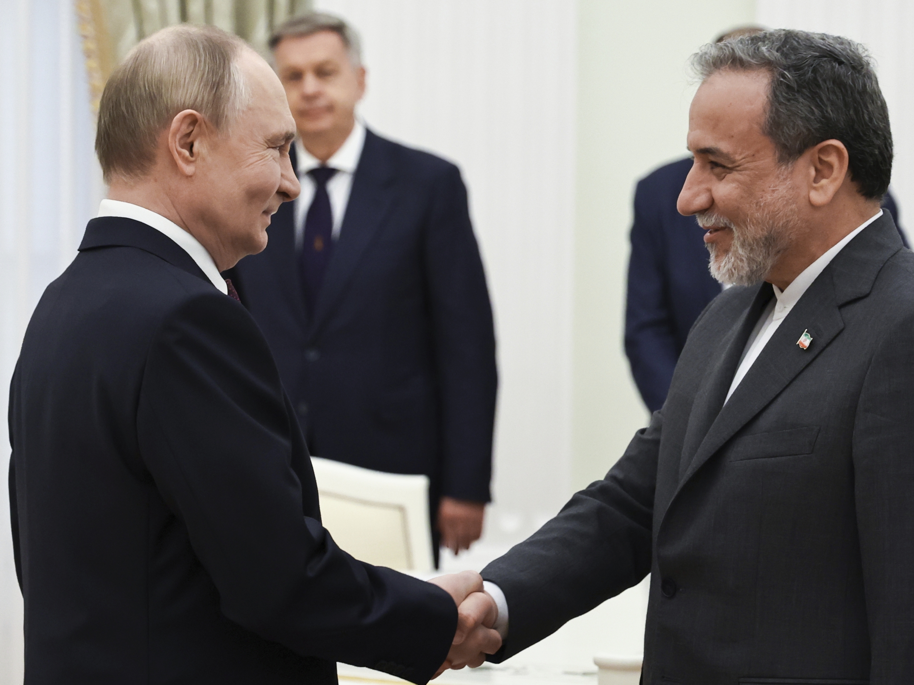 caption: Russian President Vladimir Putin (left) greets Iranian Foreign Minister Abbas Araghchi prior to their talks at the Kremlin in Moscow, Monday.