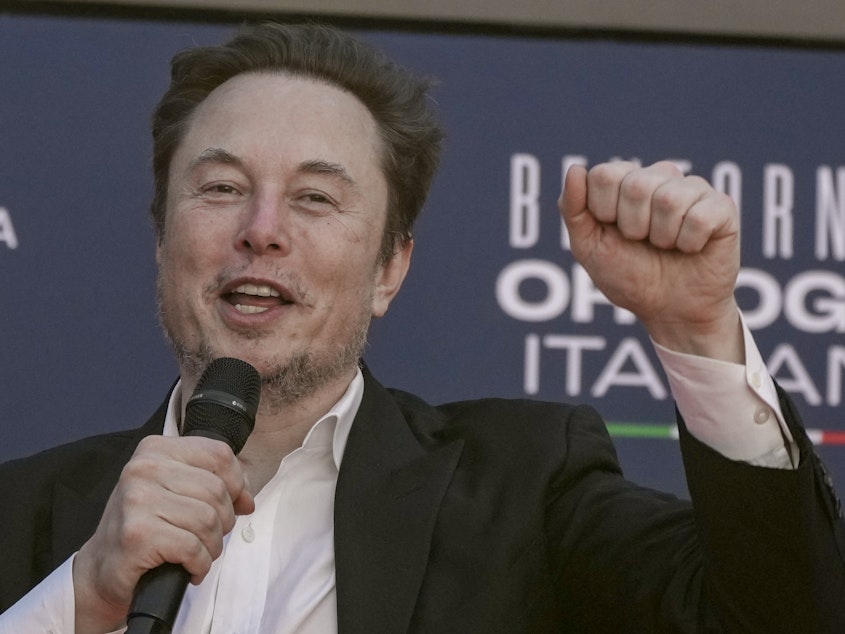 caption: Tesla CEO Elon Musk waves as he arrives at the annual political festival Atreju, organized by the Giorgia Meloni's Brothers of Italy political party, in Rome, Dec. 16, 2023.