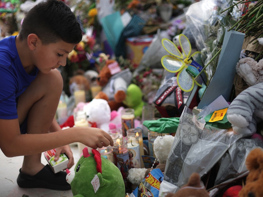 caption: A child lights candles at a memorial for the victims of a May 24 mass shooting at Robb Elementary School in Uvalde, Texas, that killed 21 people, mostly children.
