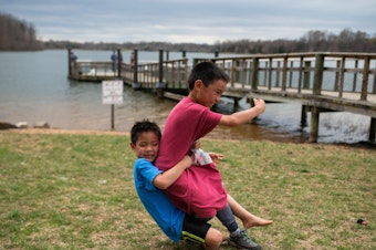 caption: Hayle tackles Henry during a game of football Black Hill Regional Park in Boyds, Md., on April 7, 2019.