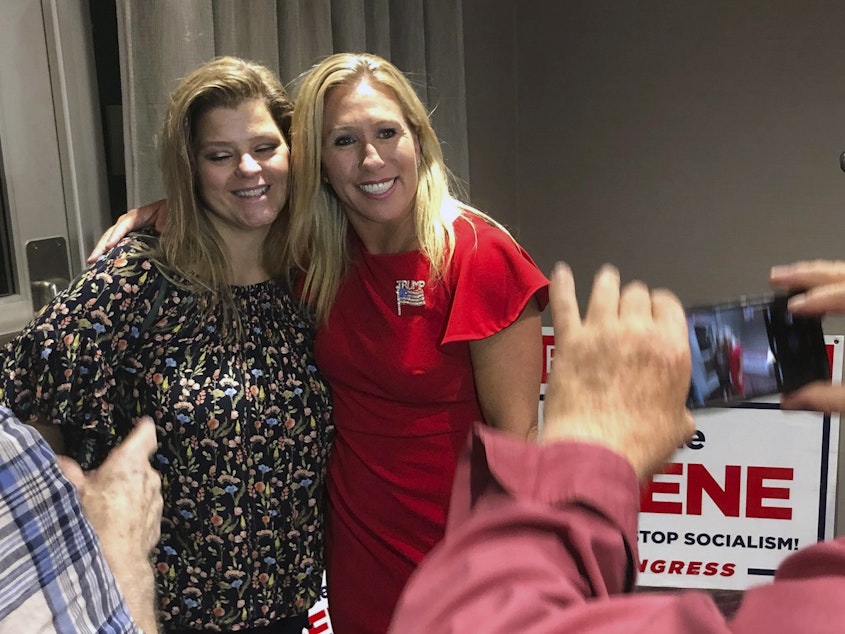 caption: Marjorie Taylor Greene, right, poses with a supporter in Rome, Ga., late Tuesday. Greene, criticized for promoting bigoted videos and supporting the far-right QAnon conspiracy theory, won the GOP nomination for Georgia's 14th Congressional District.