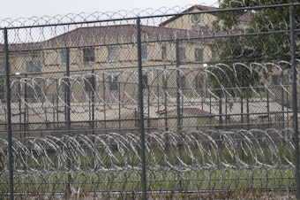 caption: Tents are seen behind wire fences near buildings of the Federal Medical Center prison in Fort Worth, Texas, on May 16, 2020. Hundreds of inmates inside the facility have tested positive for COVID-19 and several inmates have died.