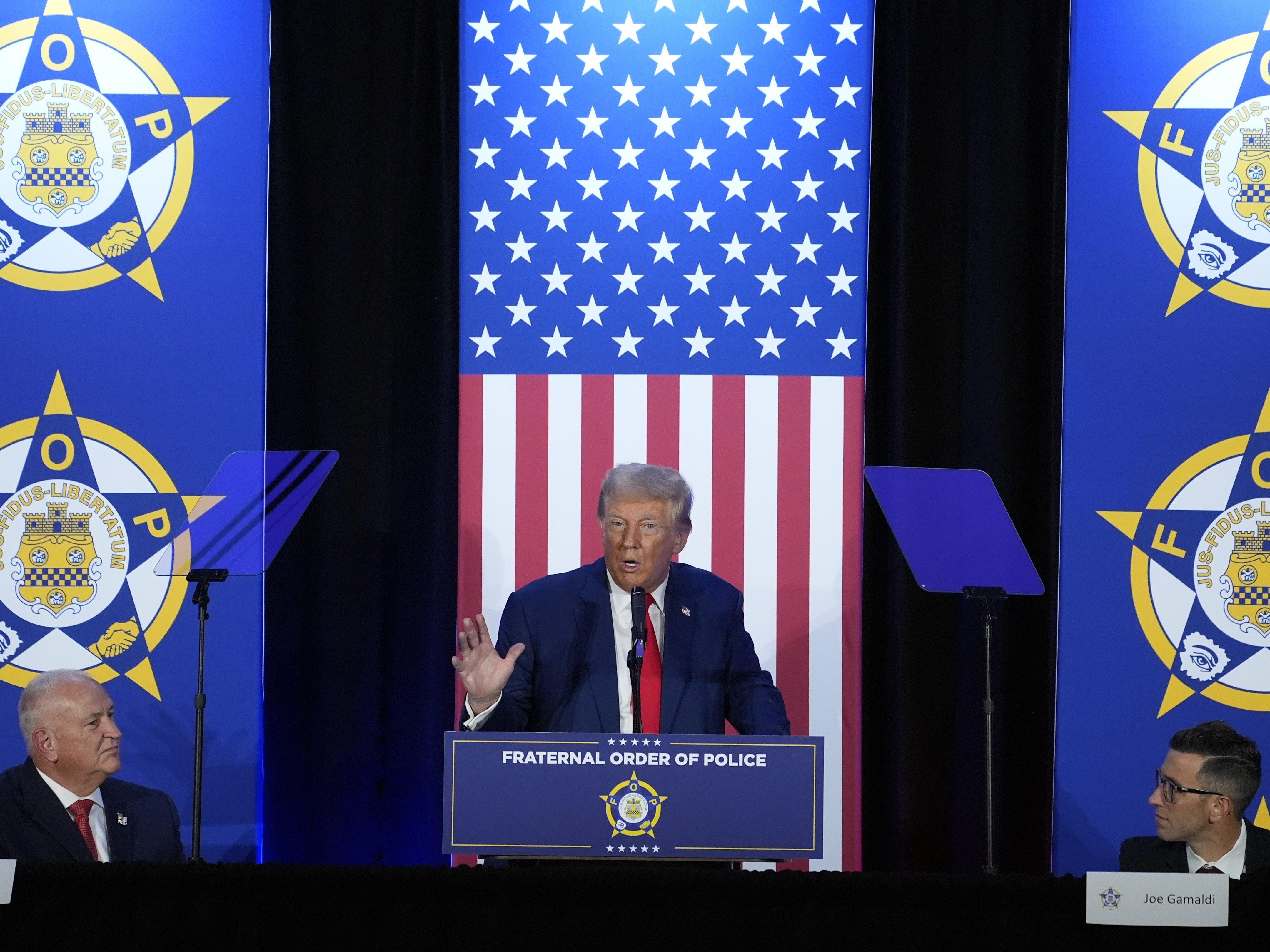 caption: President-elect Donald Trump speaks to the National Fraternal Order of Police during the campaign, in Charlotte, N.C., as FOP president Patrick Yoes, left, and FOP vice president Joe Gamaldi listen.