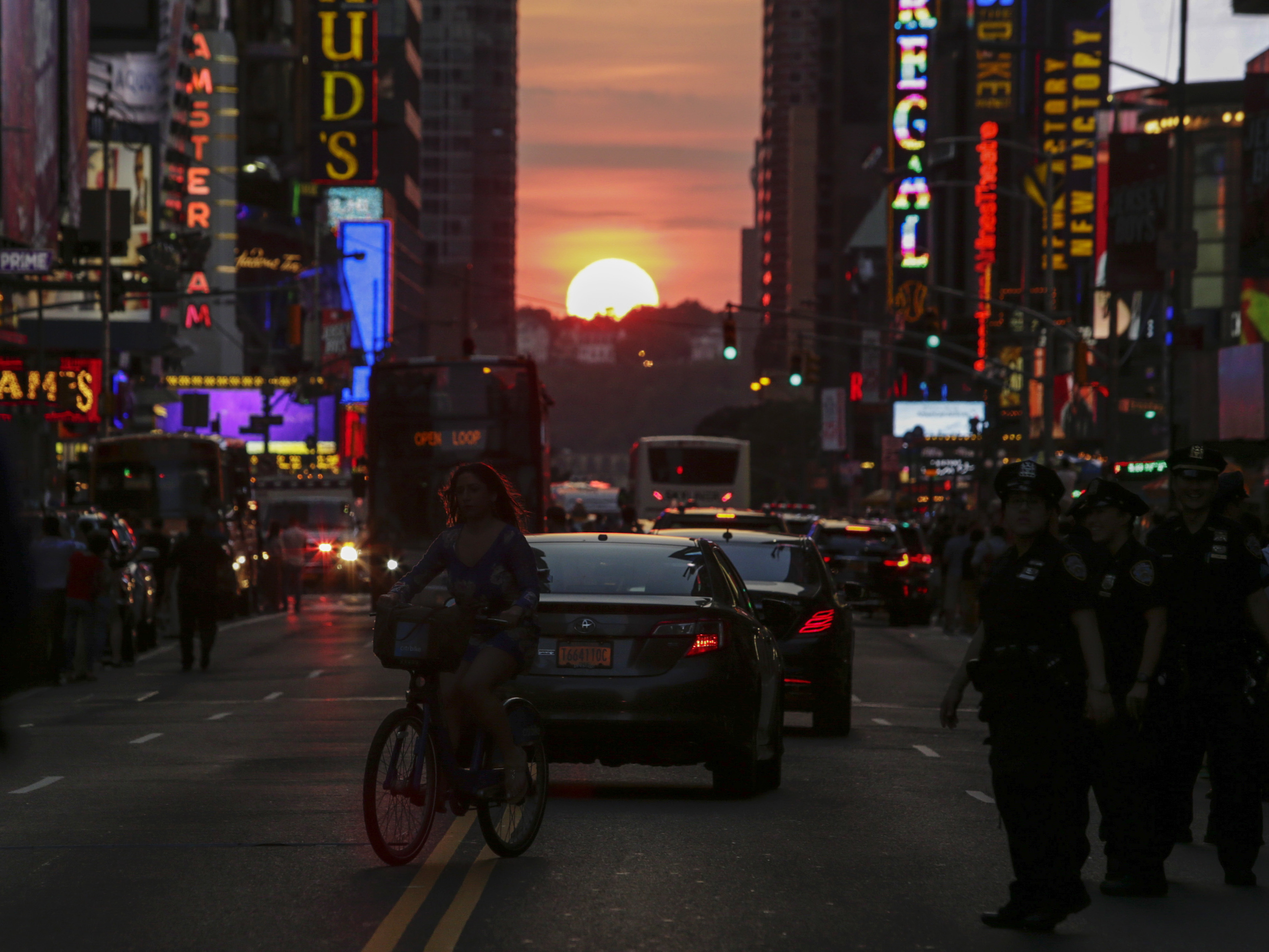 caption: A woman rides a bike on 42nd St. in New York during Manhattanhenge in 2016.