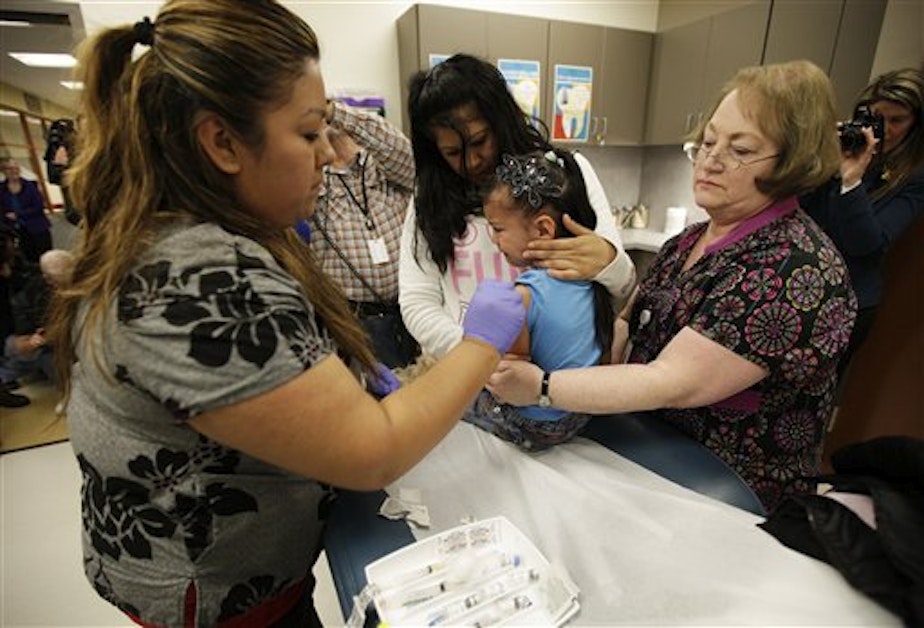caption: Nurses Fatima Guillen, left, and Fran Wendt, right, give Kimberly Magdeleno, 4, a Tdap whooping cough booster shot.