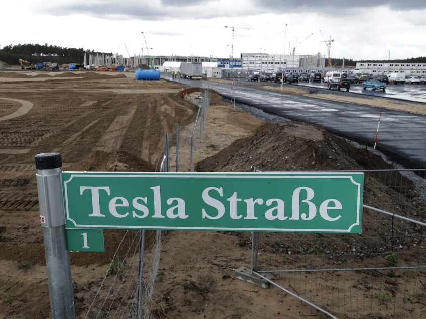 caption: A street sign says "Tesla Street 1" in front of the construction site of the Tesla Gigafactory near Berlin. The electric automaker plans to start building cars this summer at its first European production site.