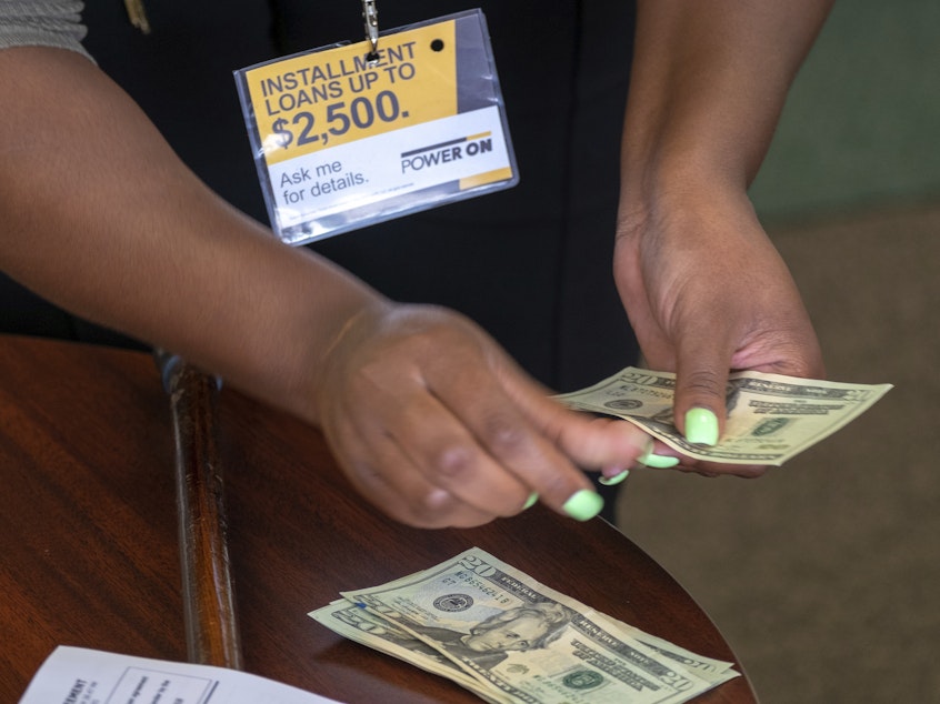 caption: A manager of a financial services store in Ballwin, Mo., counts cash being paid to a client as part of a loan in 2018. Consumer groups blasted a new payday lending rule and its timing during a pandemic that's put tens of millions of people out of work.