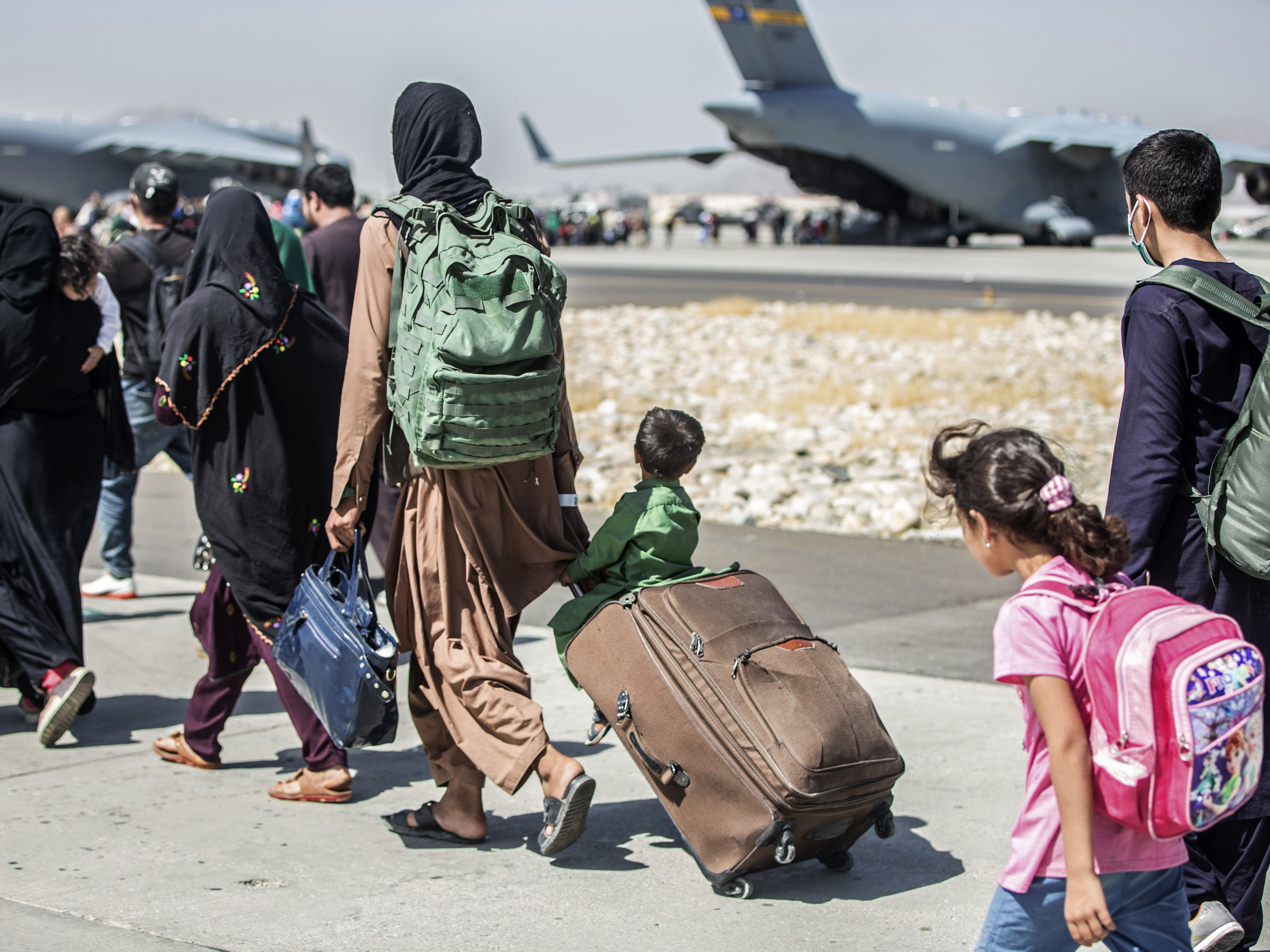 caption: Families walk toward their flight during evacuations at Hamid Karzai International Airport in Kabul, Afghanistan, on Tuesday.