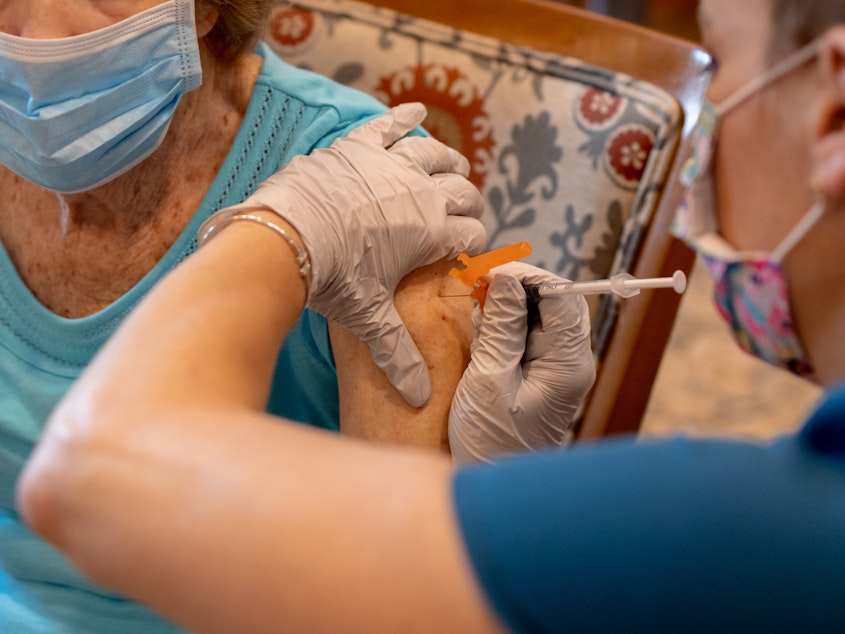 caption: A healthcare worker administers a third dose of the Pfizer-BioNTech COVID-19 vaccine at a senior living facility in Worcester, Pennsylvania, in August.