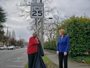 caption: Lynda Greene, Executive Director of Southeast Seattle Senior Center, hugs the new speed limit sign on Rainier Avenue South on Tuesday, December 10, 2019.