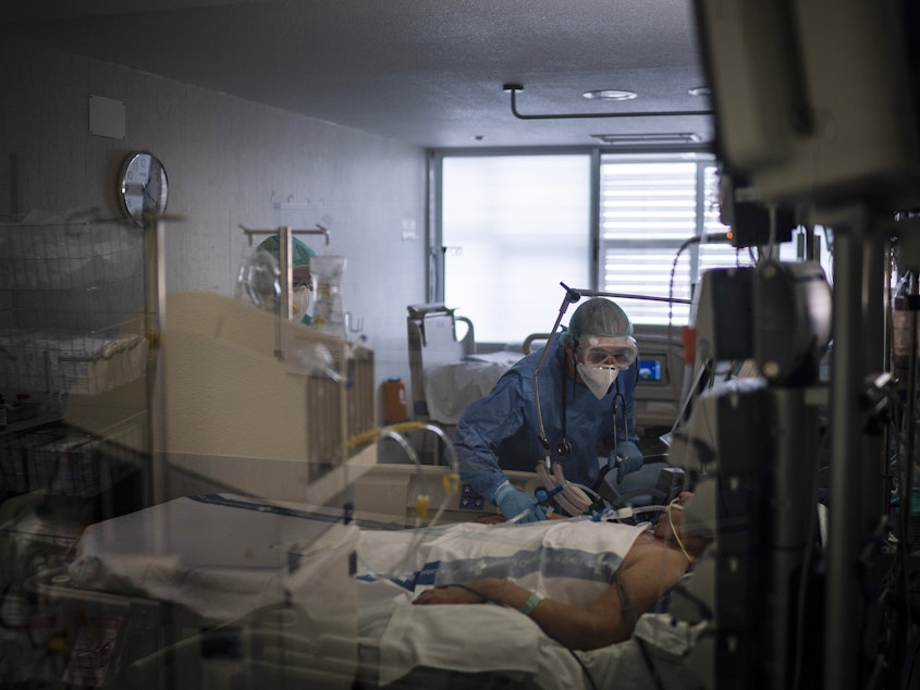 caption: Health care workers assist a COVID-19 patient in Spain. Some evidence from Europe and China suggests an overzealous immune response may be contributing to the severe illness in some patients.