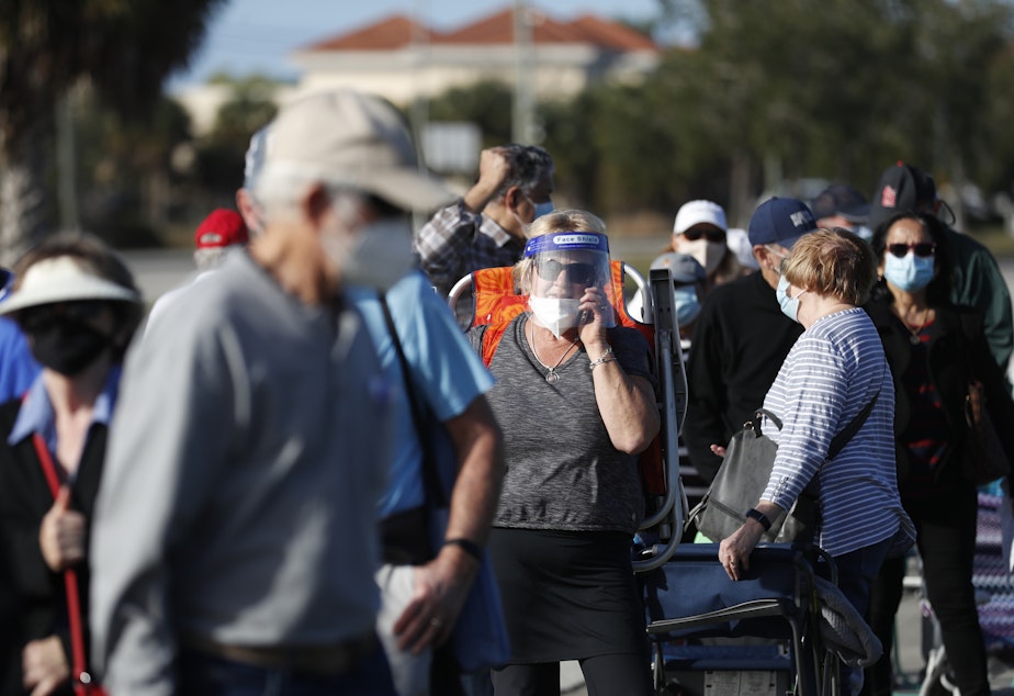 caption: Older adults and first responders wait in line to receive a COVID-19 vaccine late last month at the Lakes Regional Library in Fort Myers, Fla.