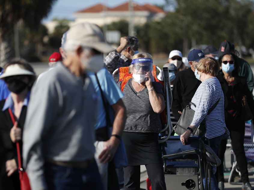 caption: Older adults and first responders wait in line to receive a COVID-19 vaccine late last month at the Lakes Regional Library in Fort Myers, Fla.