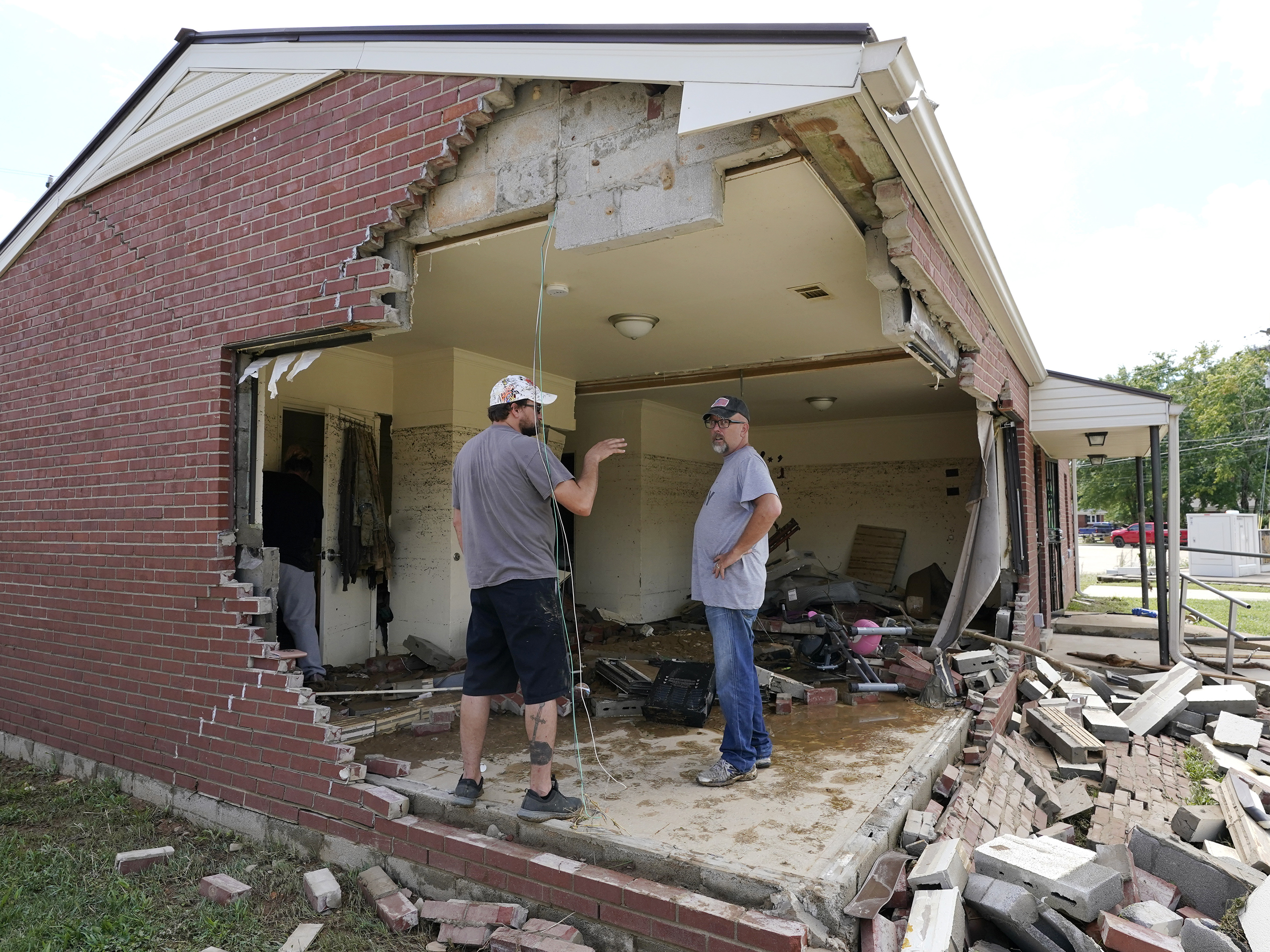 caption: Brian Mitchell, right, looks through the damaged home of his mother-in-law along with family friend Chris Hoover, left, Sunday, Aug. 22, 2021, in Waverly, Tenn. Heavy rains caused flooding Saturday in Middle Tennessee and have resulted in multiple deaths as homes and rural roads were washed away.