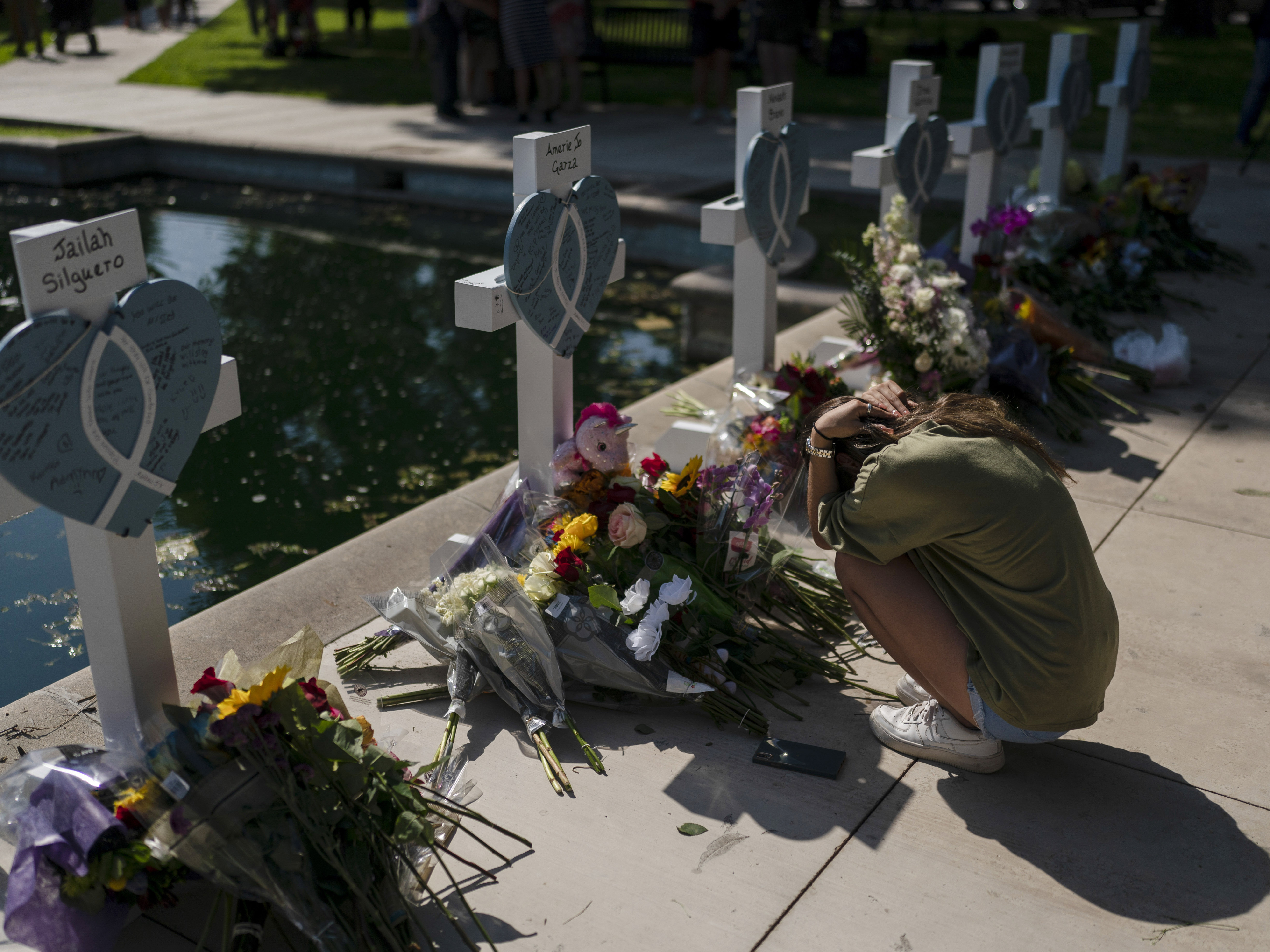 caption: Elena Mendoza, 18, grieves in front of a cross honoring her cousin, Amerie Jo Garza, one of the victims killed in this week's elementary school shooting in Uvalde, Texas, Thursday, May 26, 2022.