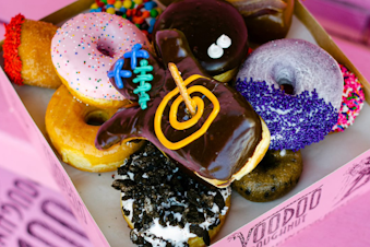 caption: A pink box of Voodoo Doughnuts. 