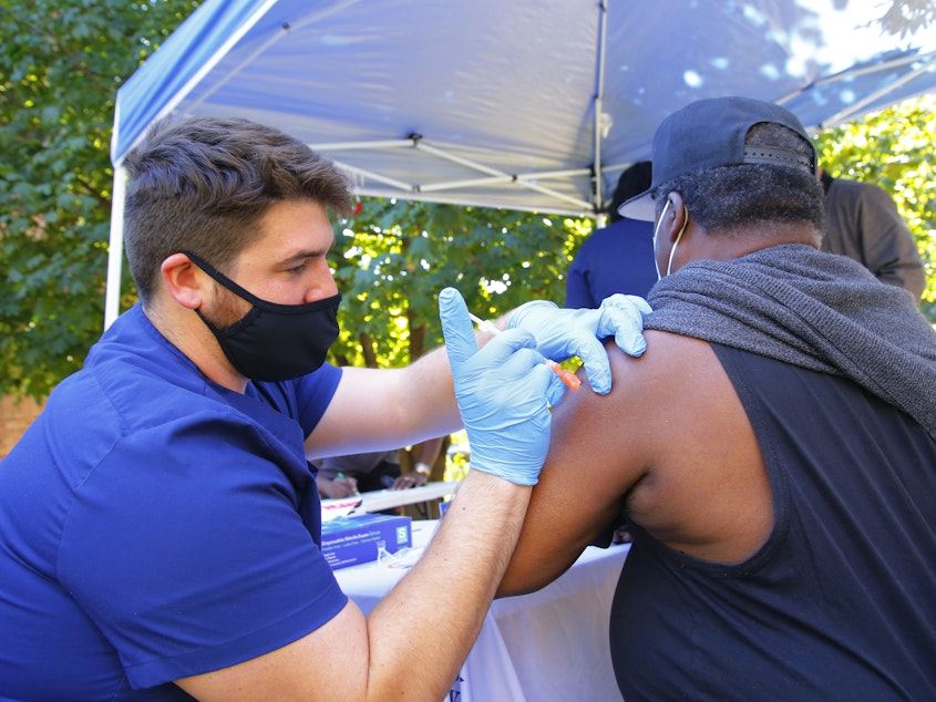 caption: A health care worker administers a Pfizer-BioNTech COVID-19 vaccine Thursday at Life of Hope Center in New York City.