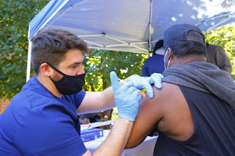 caption: A health care worker administers a Pfizer-BioNTech COVID-19 vaccine Thursday at Life of Hope Center in New York City.