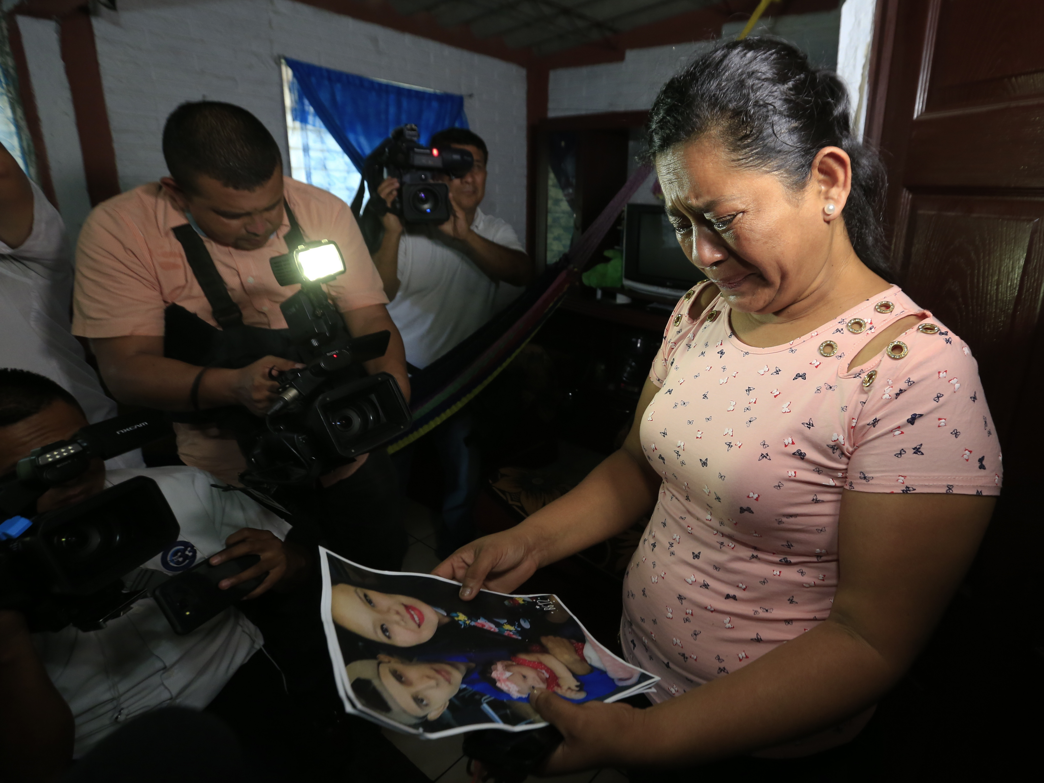 caption: Rosa Ramirez cries as she looks at photos of her son Óscar Alberto Martínez Ramírez, 25, and granddaughter Valeria, nearly 2, while speaking to journalists at her home in San Martin, El Salvador on Tuesday. The drowned bodies of her son and granddaughter were found Monday morning on the banks of the Rio Grande.