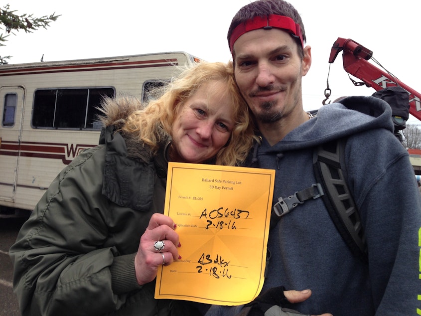caption: Wanda Williams, a former nurse who has been homeless for three years, and her roommate Tim Pugsley hold up a permit that allows them to stay in Seattle's RV Safe Lot in Ballard. 