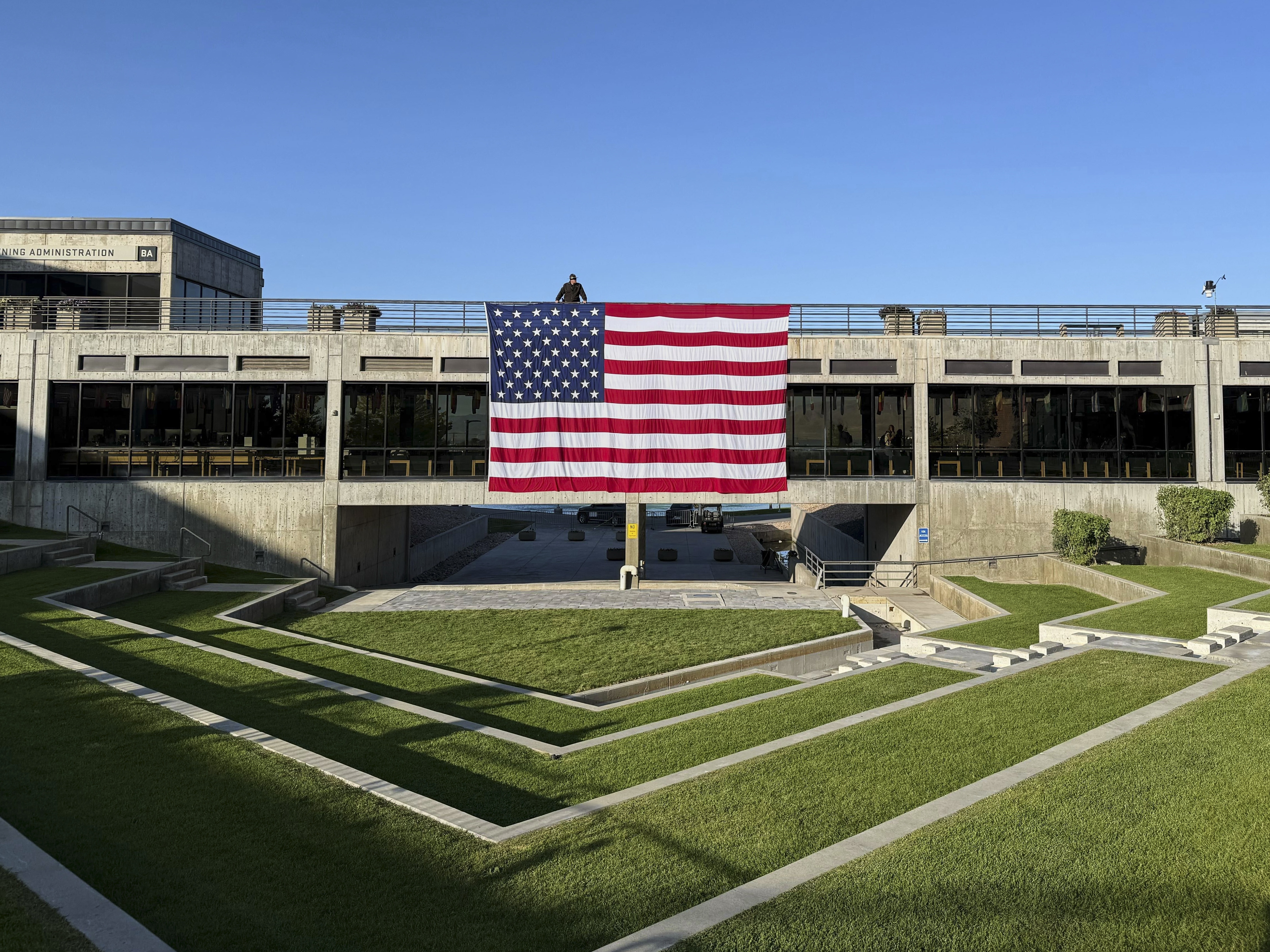 caption: A national flag hangs over the site where conservative activist Charlie Kirk was shot and killed at Utah Valley University last week. Experts say foreign governments have been doing their best to spin events to fit their narratives.
