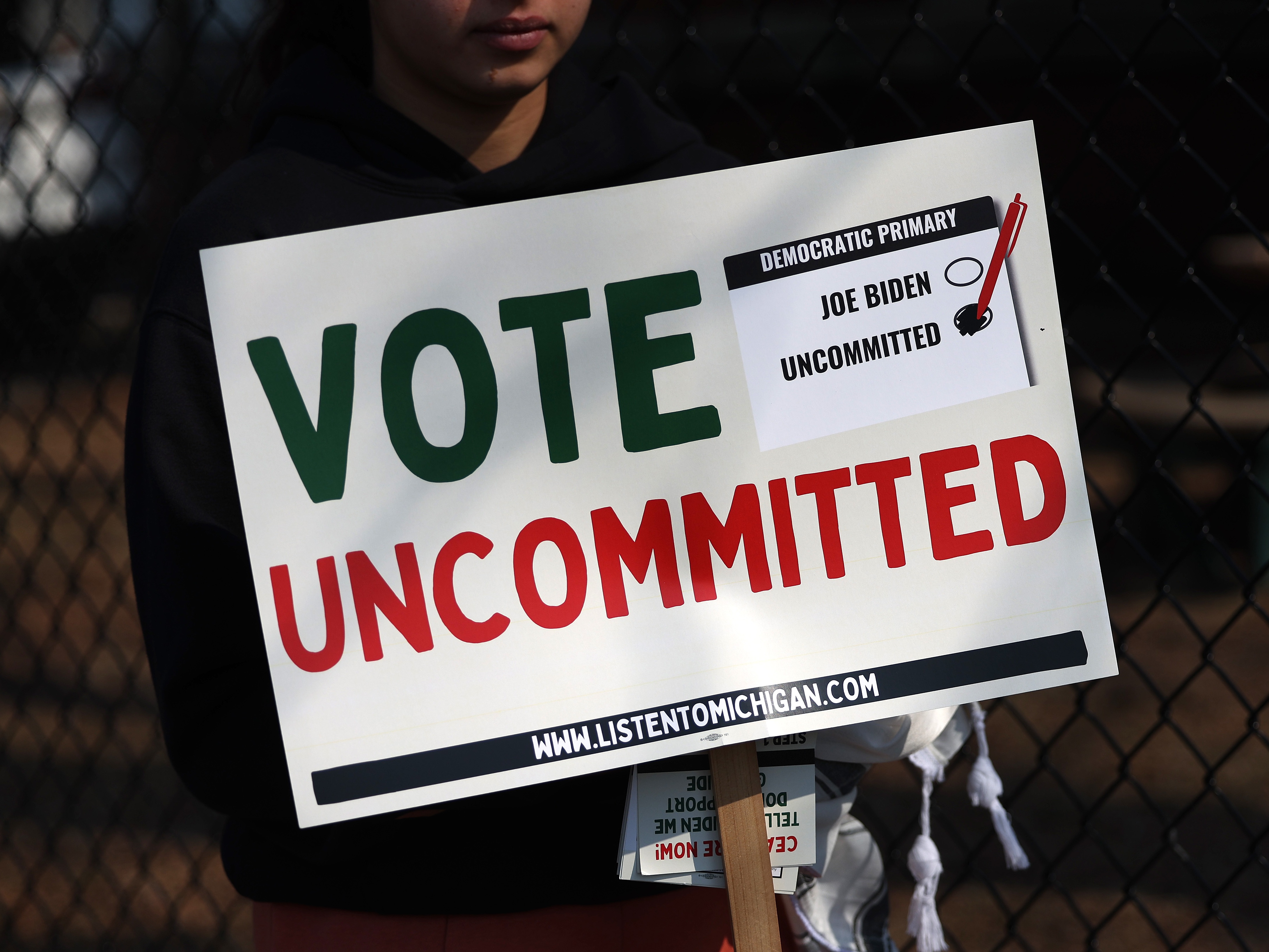 caption: An "uncommitted" voter holds a sign opposing President Biden’s policy toward Israel’s war in Gaza, outside a polling place in Dearborn, Mich., ahead of that state's presidential primary in February.