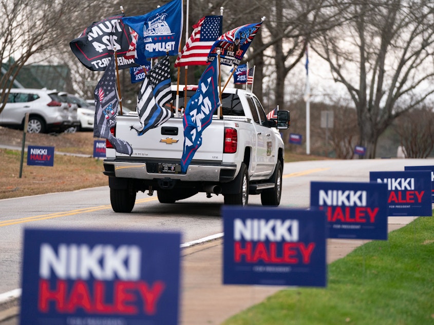 caption: A supporter of former President Donald Trump drives past campaign signs for Republican presidential candidate Nikki Haley in Irmo, South Carolina. The state's Republican presidential primary is on Feb. 24.