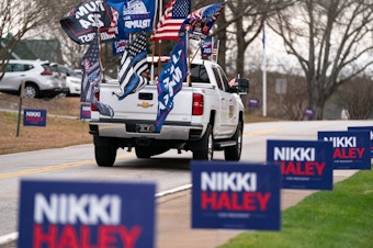 caption: A supporter of former President Donald Trump drives past campaign signs for Republican presidential candidate Nikki Haley in Irmo, South Carolina. The state's Republican presidential primary is on Feb. 24.