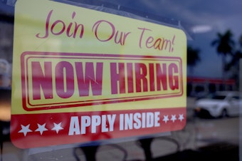 caption: A sign seeking job applicants is seen in the window of a restaurant in Miami, Florida, on May 5, 2023.