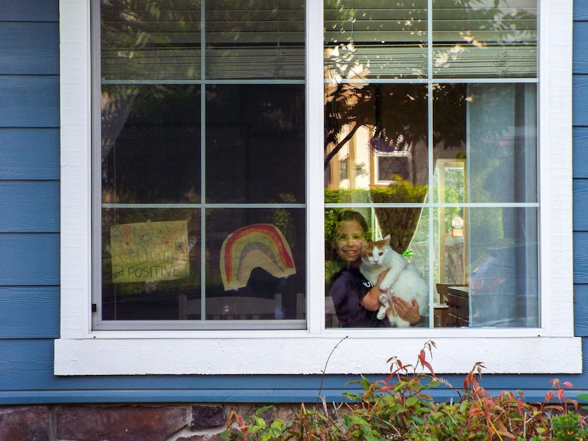 caption: Leah Russel, age 10, poses with her cat Toffee with colorful drawings of a rainbow and drawings of flowers that say “Stay Positive.” Leah said she wants to keep people happy and motivate them to be strong during the Covid-19 crisis.