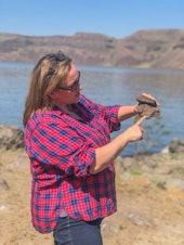 caption: Casie Davidson, a scientist at Pacific Northwest National Laboratory, points out how basalt rocks are layered on top of each other. The rocks formed millions of years ago after volcanic eruptions and could now help store carbon dioxide.