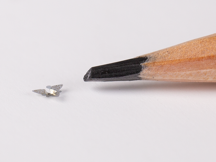 caption: A 3D microflier next to a pencil tip for scale.