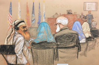 caption: Alleged Sept. 11 mastermind Khalid Sheikh Mohammed (far left) consults with his defense attorneys in the U.S. military courtroom in Guantánamo Bay, Cuba, as a man who waterboarded him, retired Air Force psychologist James Mitchell, takes the stand.