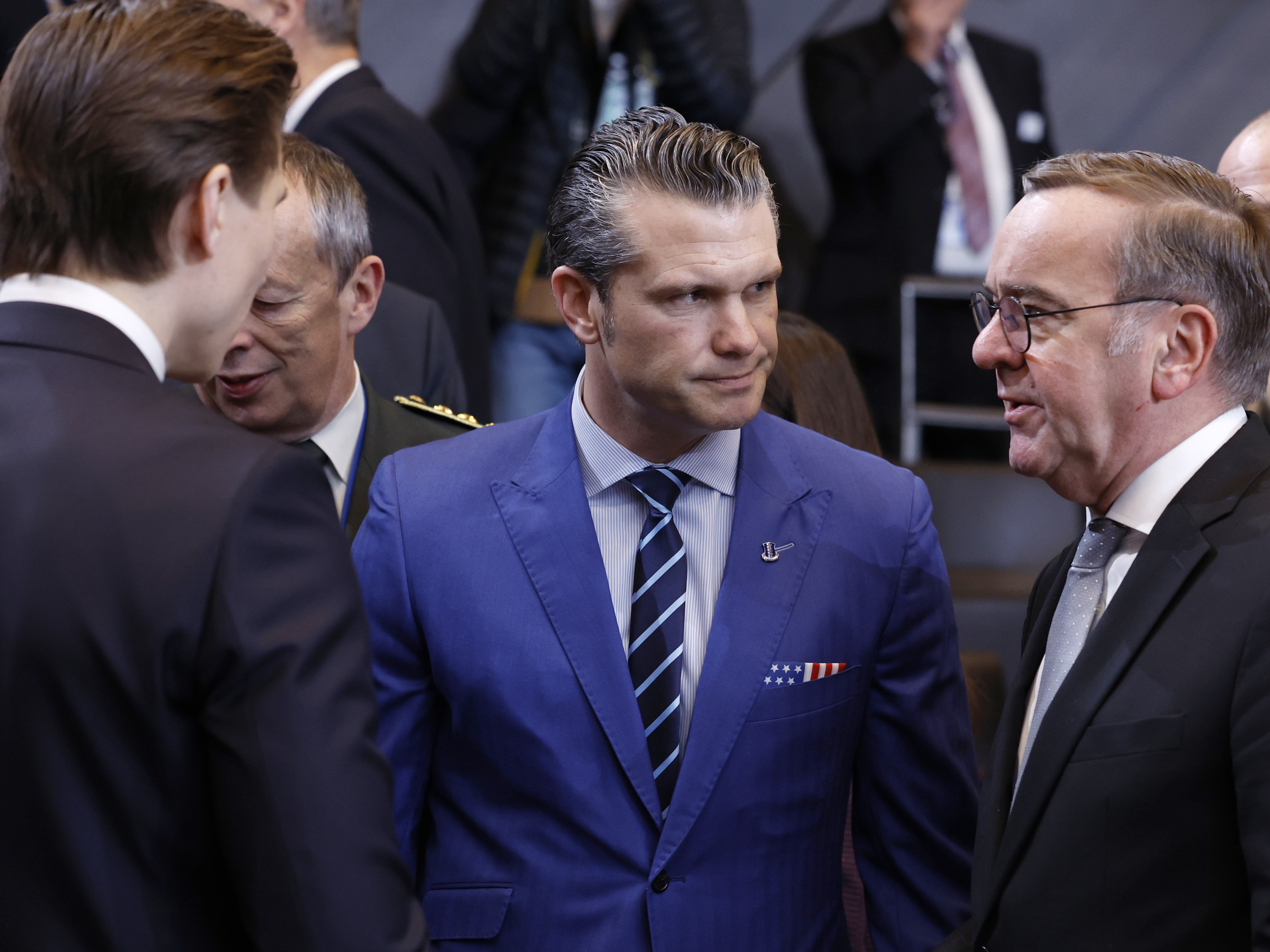 caption: U.S. Defense Secretary Pete Hegseth (center) speaks with German Defense Minister Boris Pistorius (right) and Finland's defense minister, Antti Hakkanen, at NATO headquarters in Brussels, Thursday.