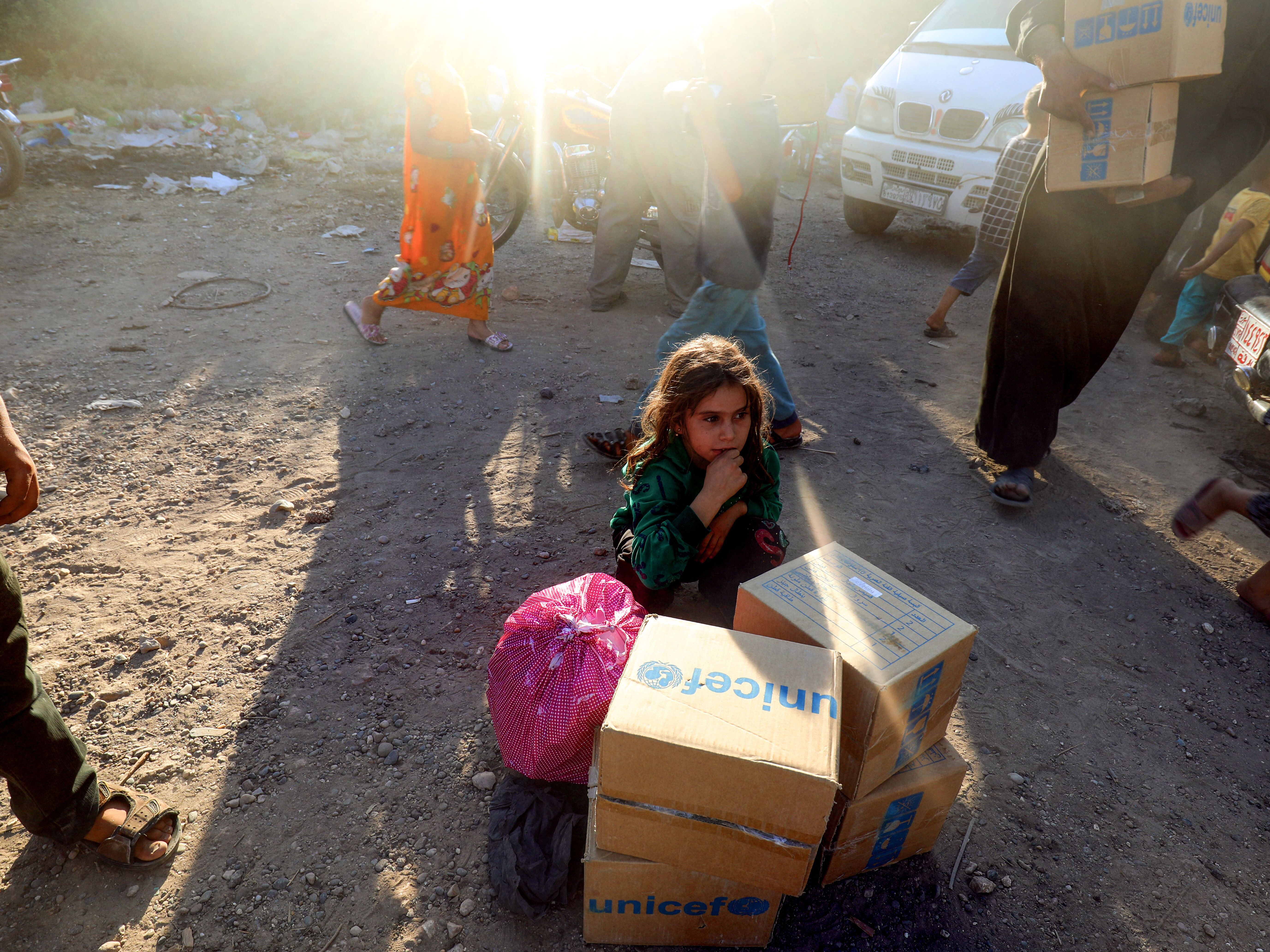 caption: A girl sits behind humanitarian aid boxes delivered by UNICEF at a temporary camp in the town of Tabqa, Syria, on Aug. 4, 2017. The rescission bill cut U.S. funds for this U.N. agency that works with children.