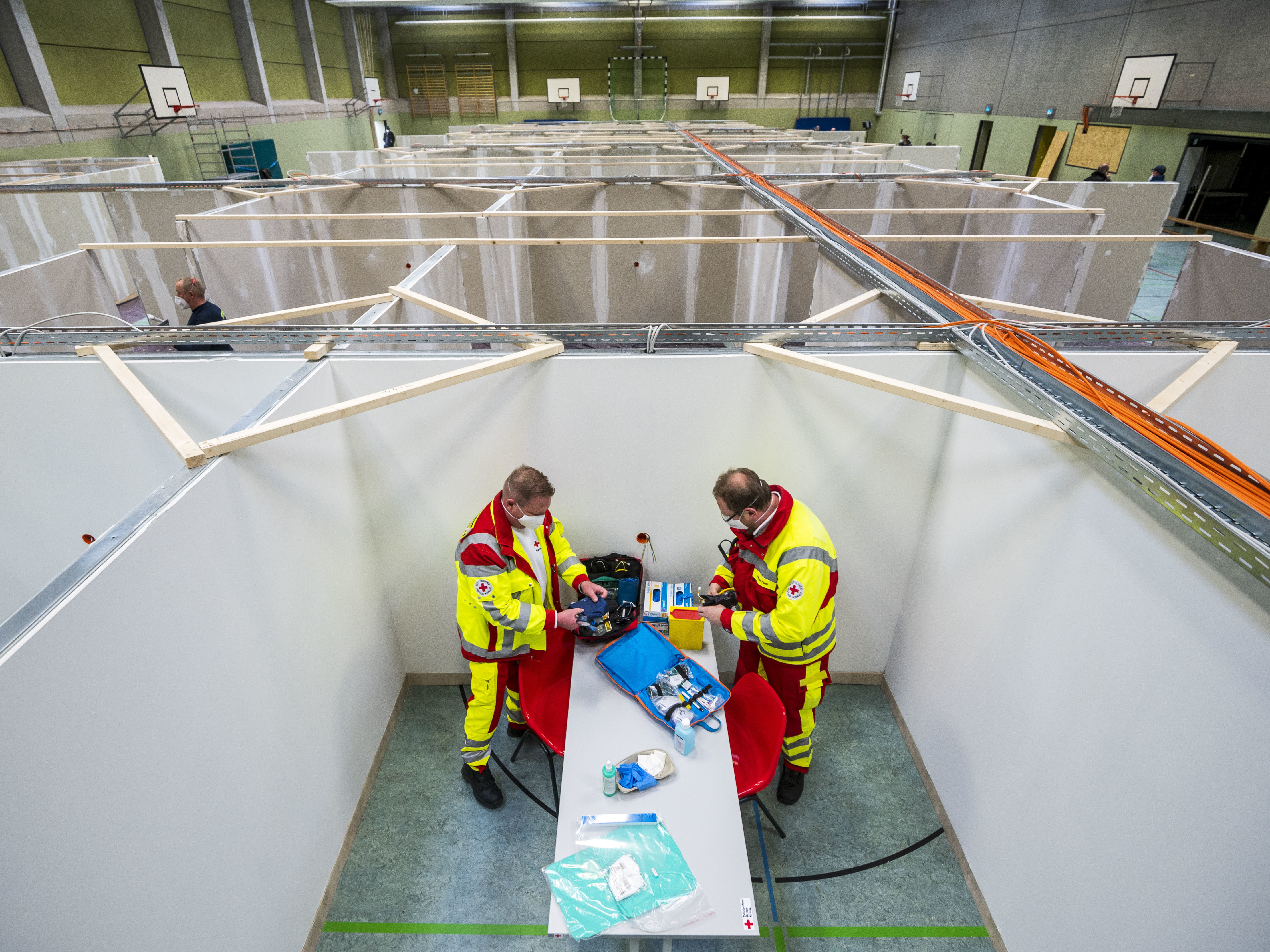 caption: The pending arrival of vaccines has brought "hope for a brighter future," the OECD says. Here, workers from the Red Cross and the Federal Agency for Technical Relief help set up a center for COVID-19 vaccinations in a gymnasium in Eschwege, Germany.