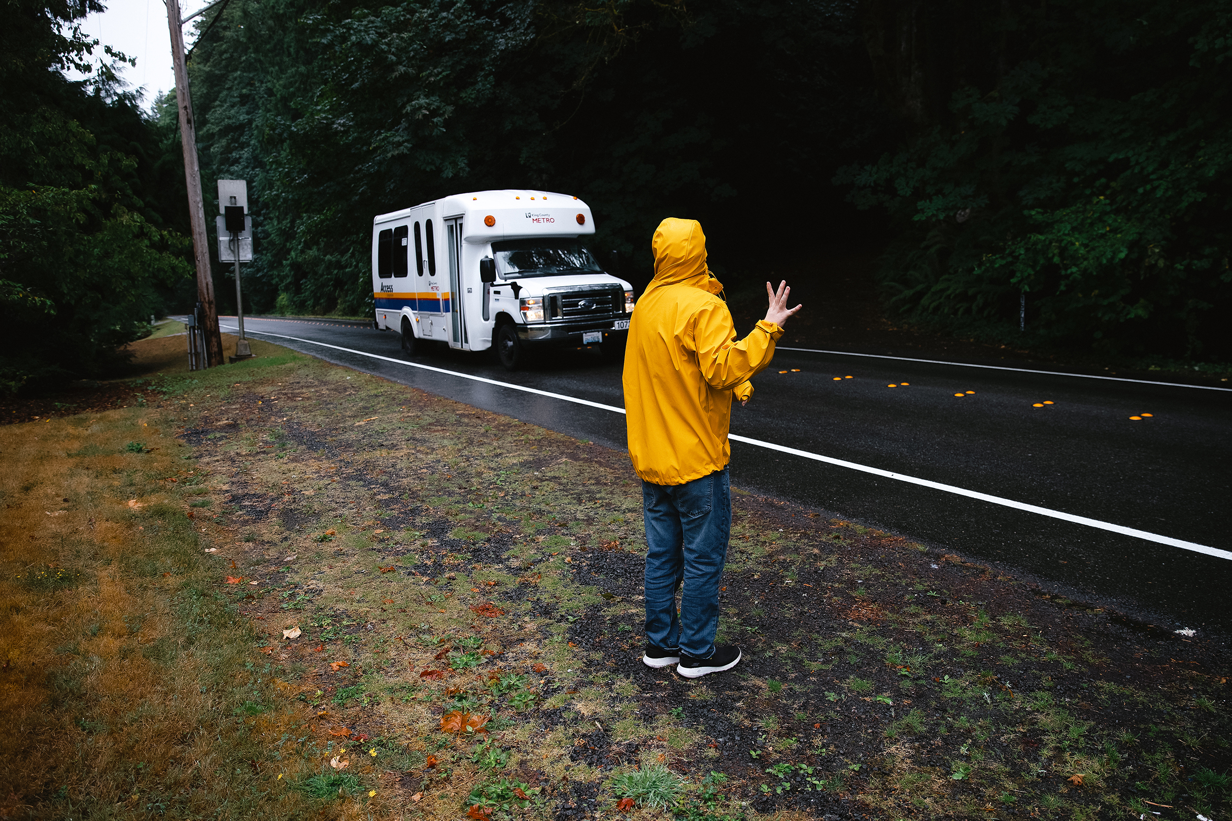 caption: Nate Nemhauser, 21, waves to a King County Metro Access bus driver before a shift at work, outside of his home on Friday, August 15, 2025, in Bellevue. 
