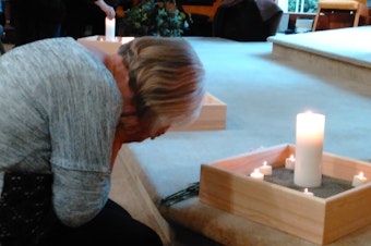 caption: Community members light candles for the victims of the Cascade mall shooting