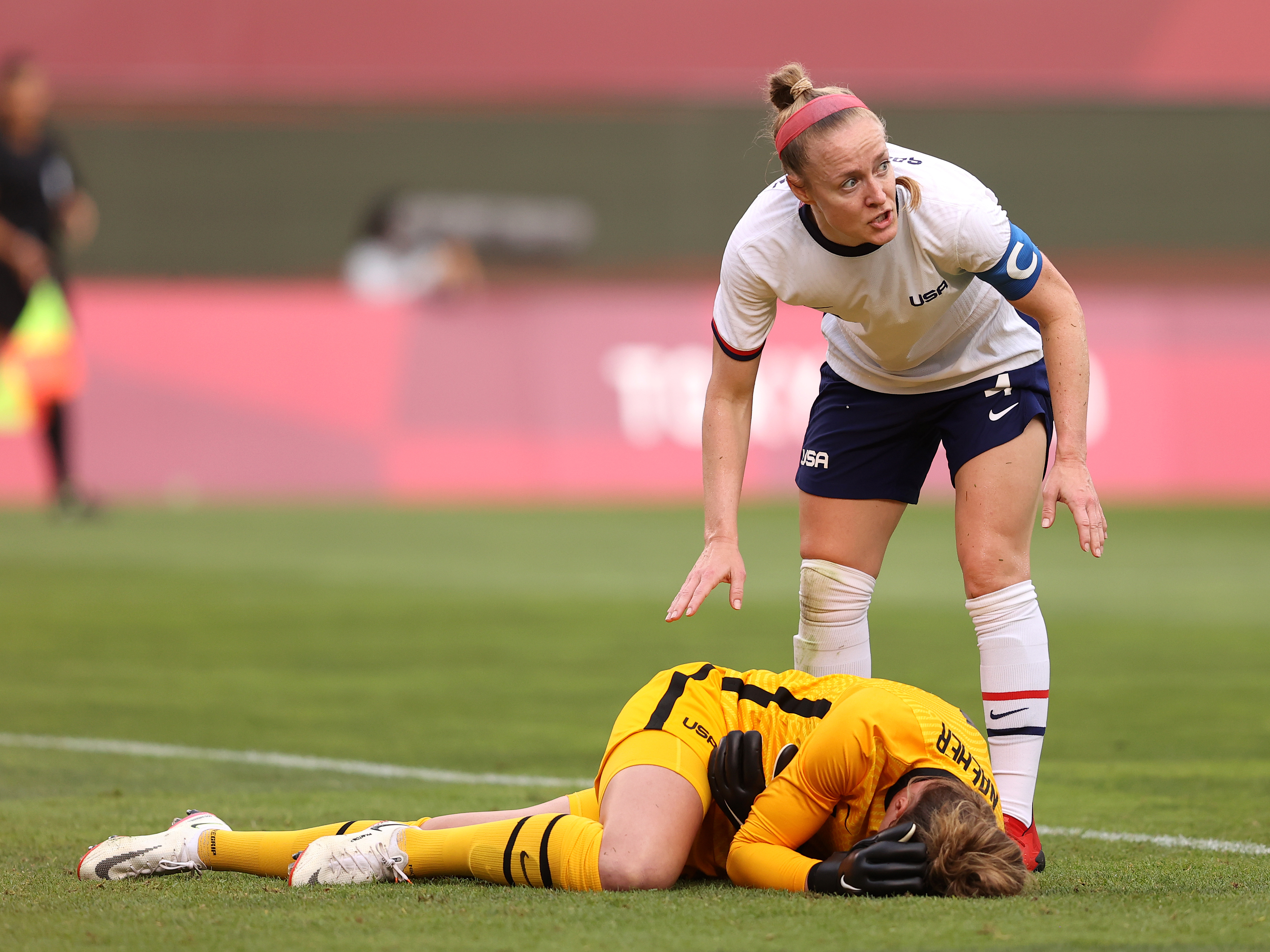 caption: U.S. goalkeeper Alyssa Naeher lies injured as Becky Sauerbrunn checks on her during the women's semifinal match between Team USA and Canada on Monday at the Tokyo Olympic Games at Kashima Stadium.
